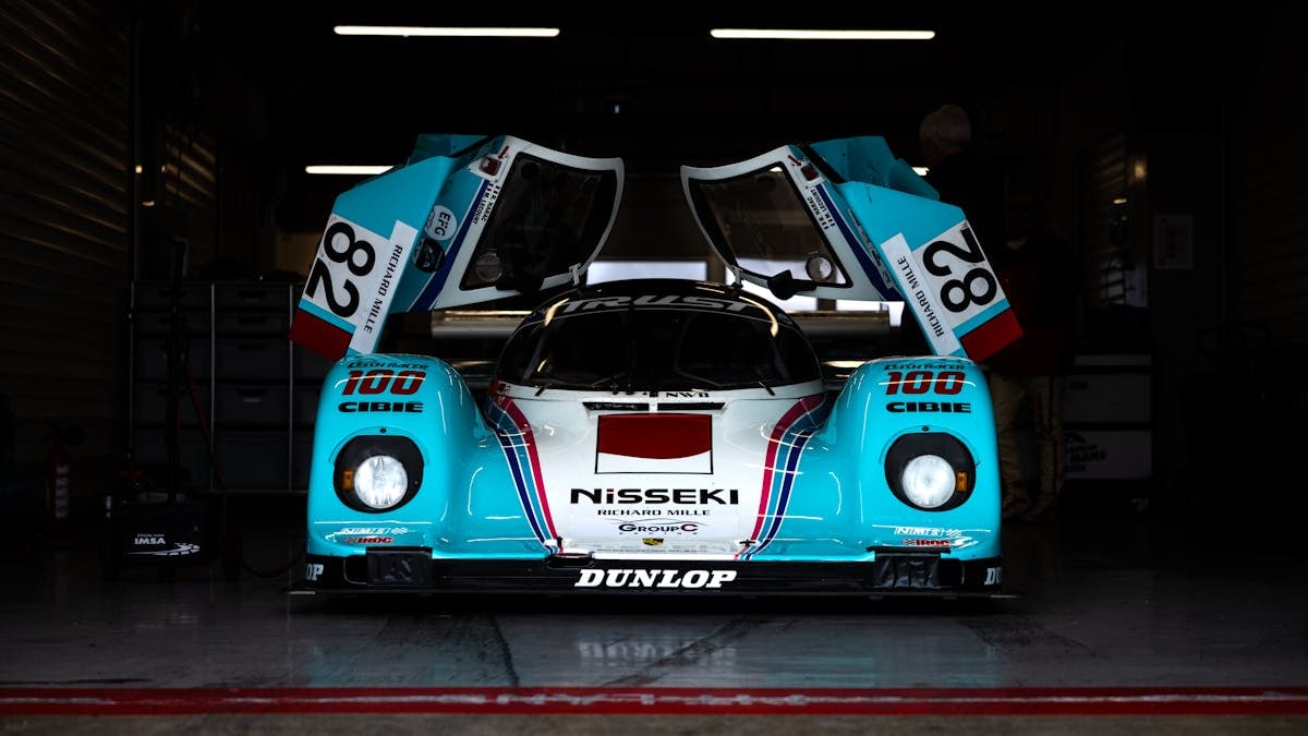 Vintage racing car with distinctive livery and open doors in a dimly lit garage.